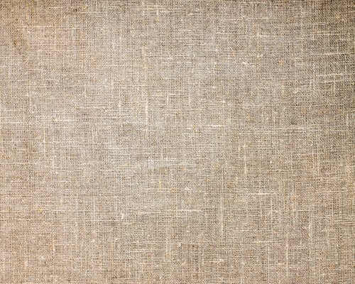 A heap of dark organic raisins scattered neatly over a rough linen fabric texture
