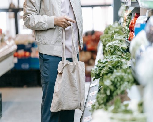 A close-up shot of a shopper examining nutritional facts printed on a food bag inside a bright grocery store corridor